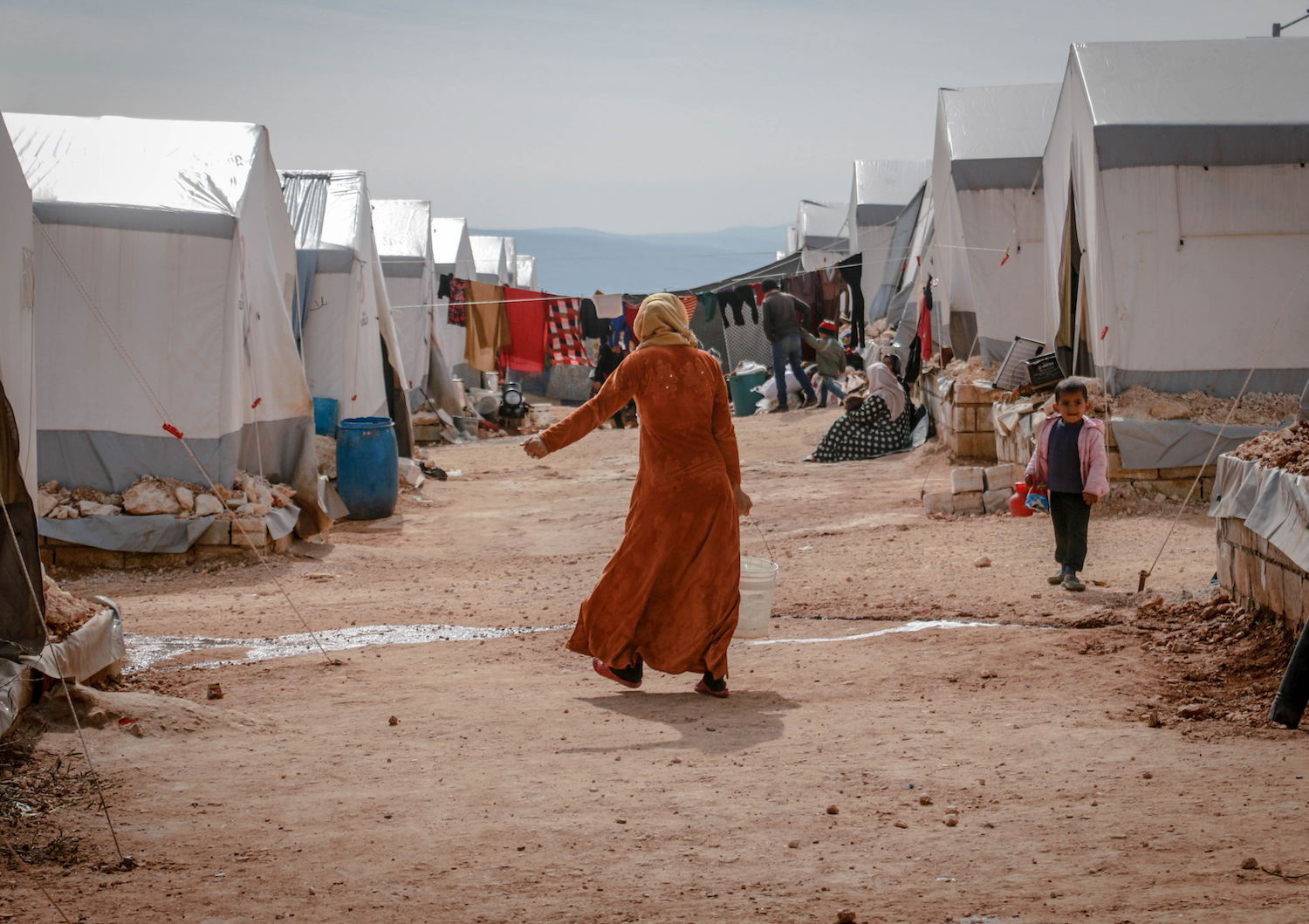 refugee camp, a woman carrying a bucket of water